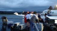 people loading or unloading pet crates from a private plane.