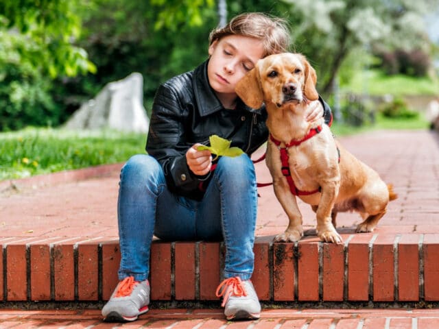 A young girl leaning on a dog.