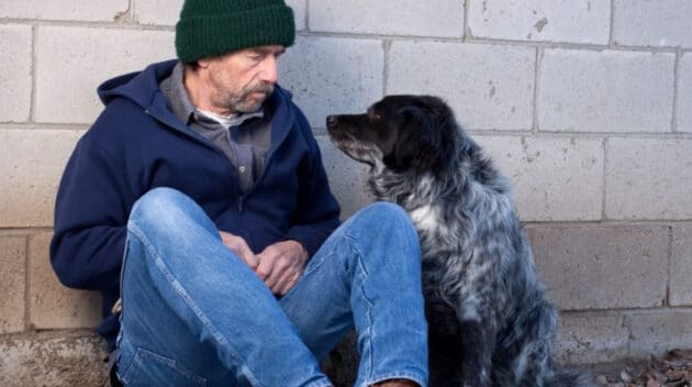 A man sitting next to a dog.