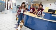 A woman and her dog inside Monadnock Humane Society, along with two staff members behind a front desk.