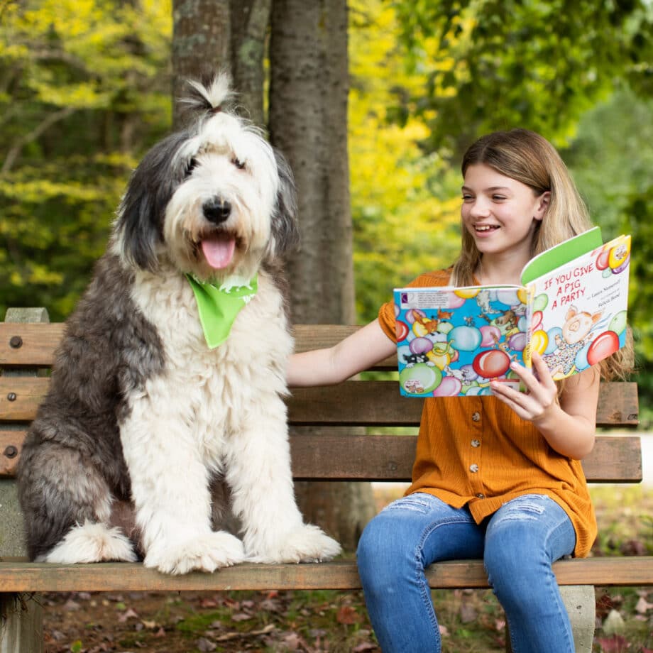 A young girl reading to a dog.