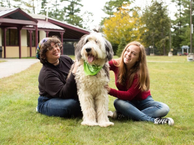 two young women petting a dog.