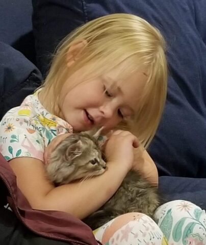 A young girl embracing a cat.