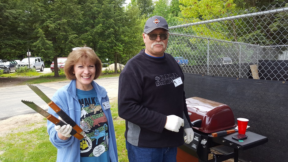 man and woman at a grill at a bbq.
