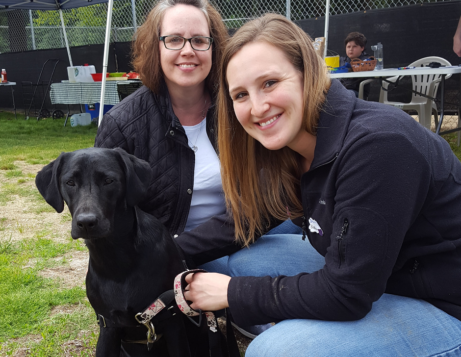 two women with a black dog.