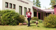 A woman walking a dog outside the entrance of the Monadnock Humane Society building.