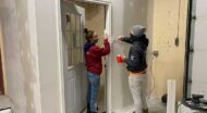 two people working on doorway in building under construction.