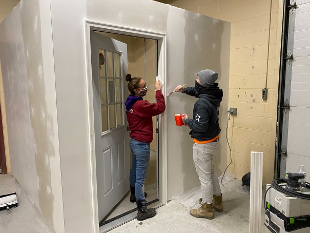 two people working on doorway in building under construction.