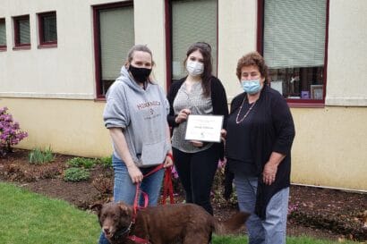 three women holding an award with a dog at their feet.