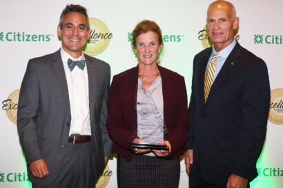 two men and a women standing next to each other and holding an award.