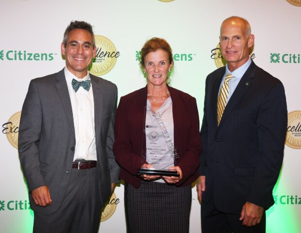 two men and a women standing next to each other and holding an award.